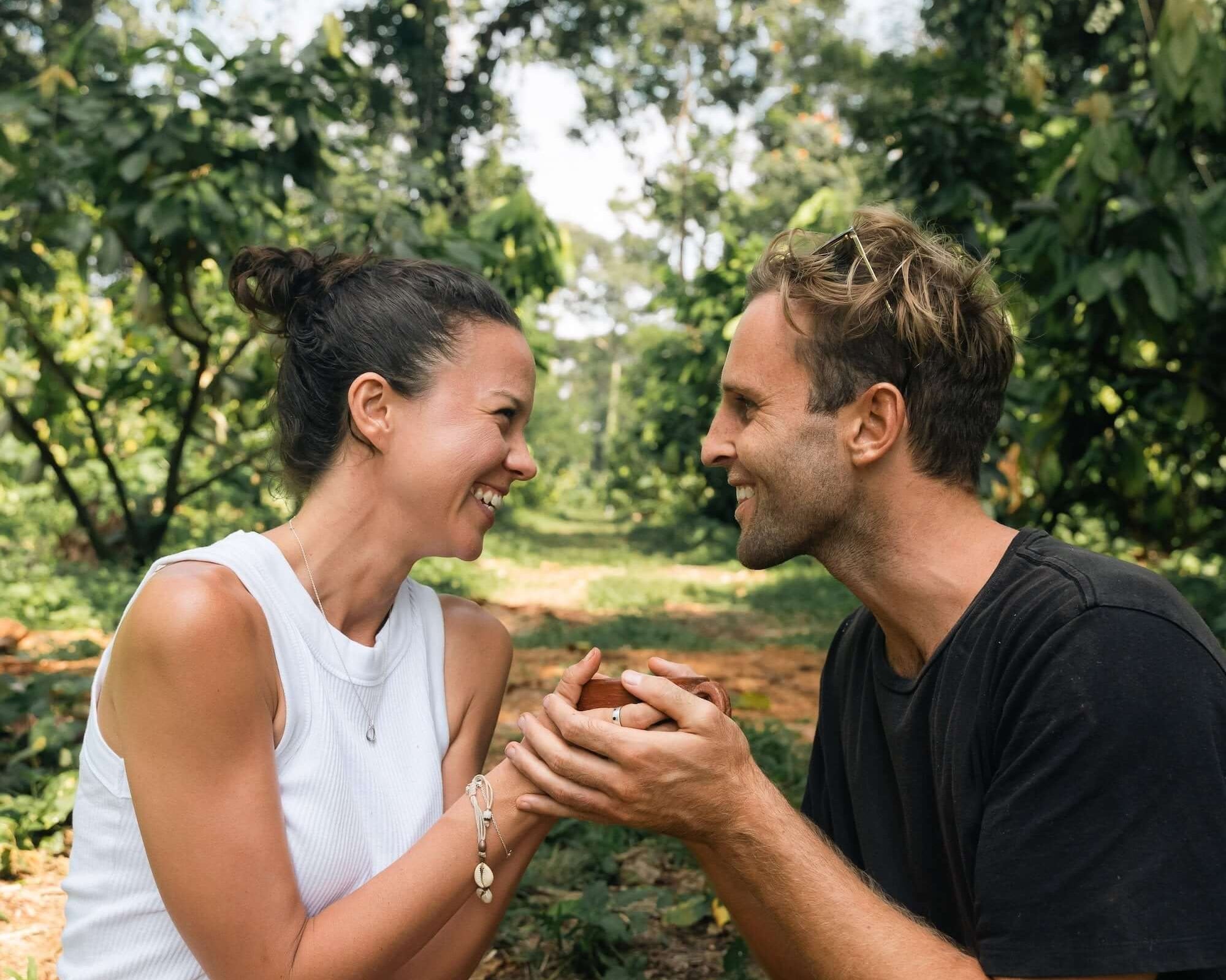 Couple enjoying cacao in a lush forest, highlighting the connection with ceremonial cacao.