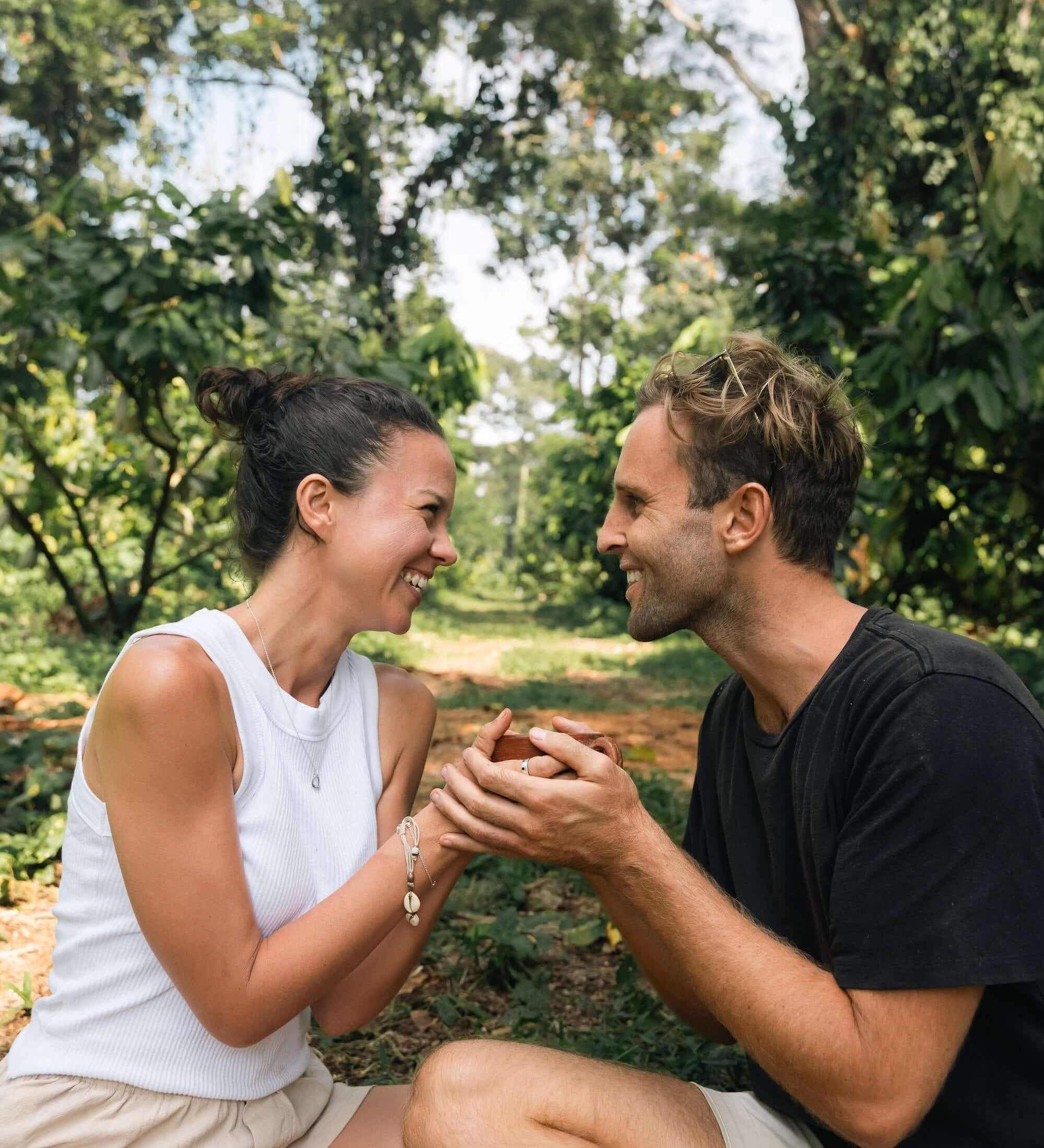 Couple enjoying cacao in a lush forest, highlighting the connection with ceremonial cacao.