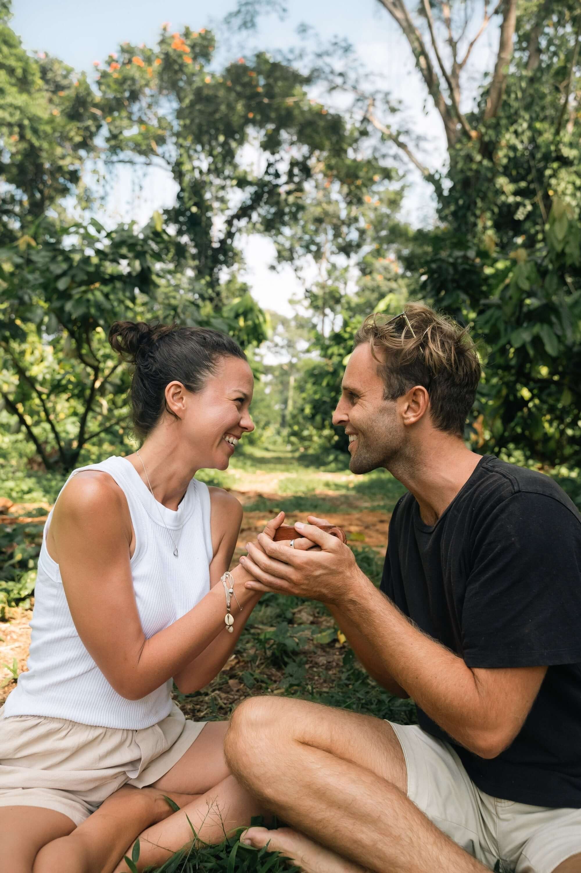 Couple enjoying cacao in a lush forest, highlighting the connection with ceremonial cacao.