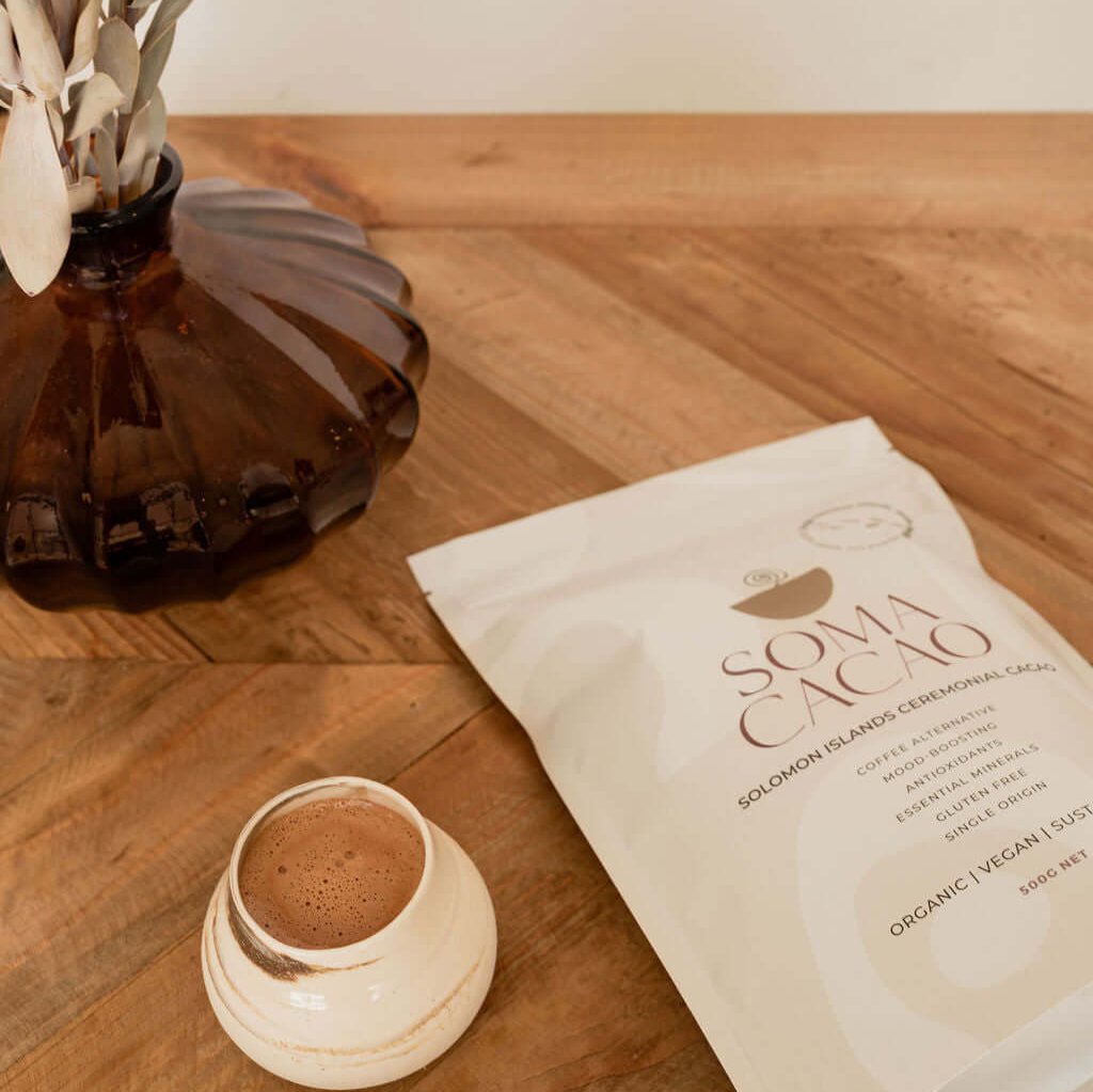 Solomon Islands Ceremonial Cacao packaging next to a cup on a wooden table, featuring premium quality organic ingredients.