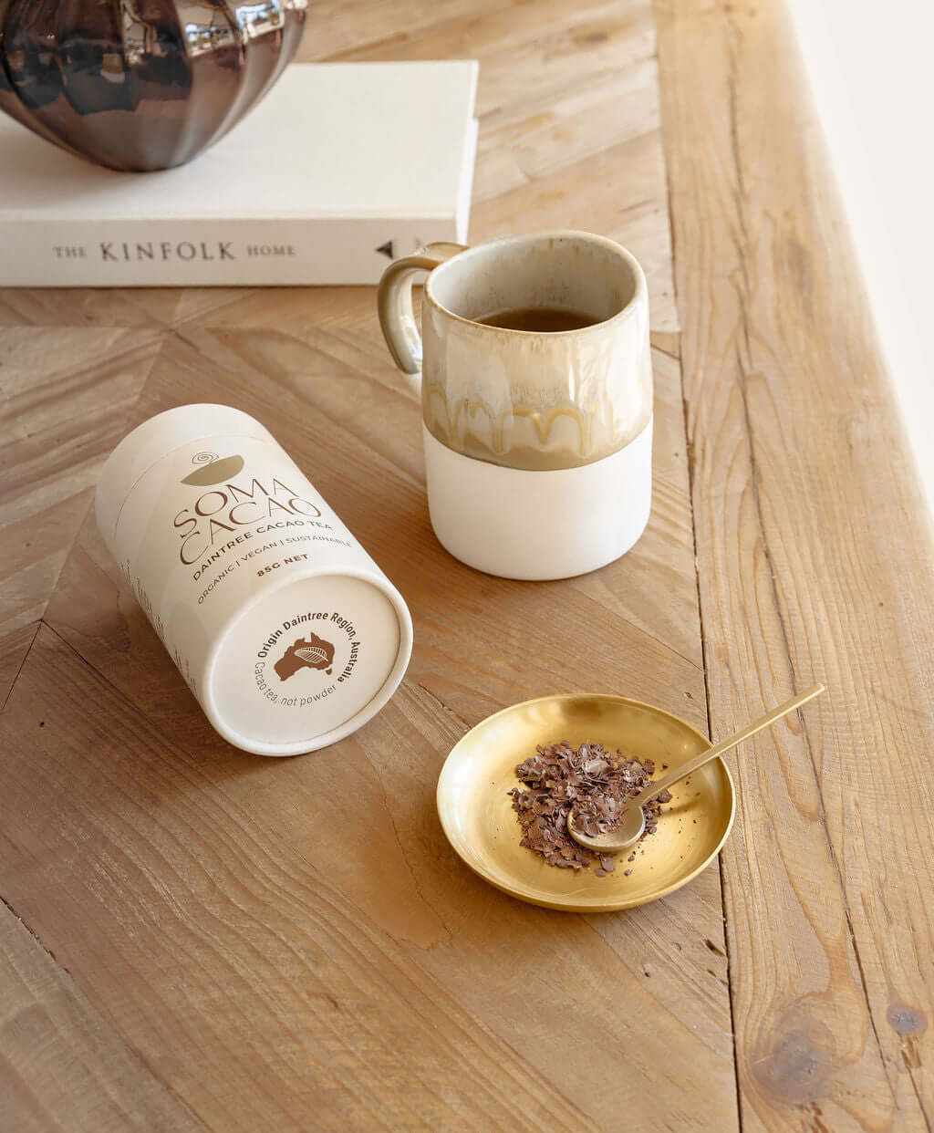 Daintree Cacao Tea with Brass Tea Scoop on wooden table, highlighting ceremonial cacao drink and health benefits.