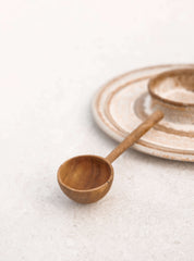 Wooden scoop on ceramic plates for ceremonial cacao preparation and cacao drinks.